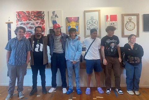 Hori and the group of rangatahi artists standing in front of their work at the Hōmai Haumaru exhibition opening.